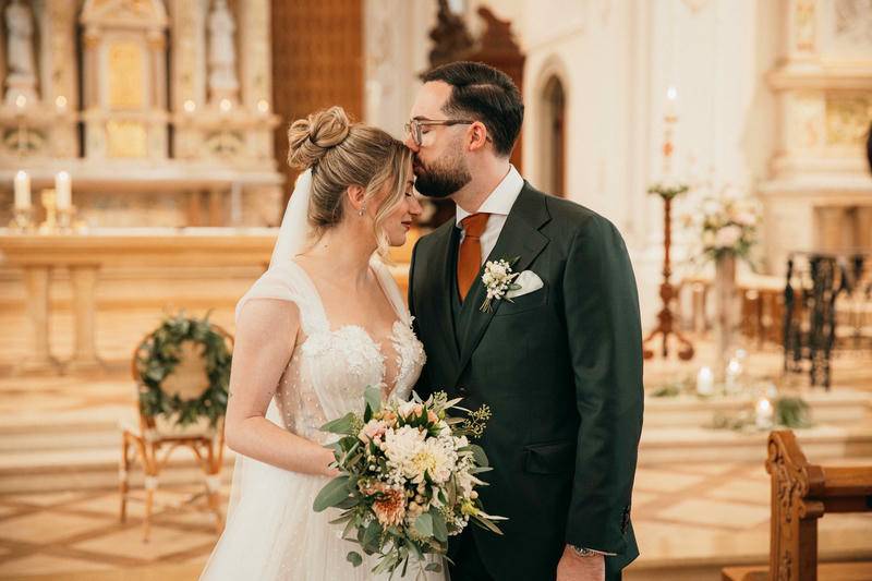 Fröhliches Brautpaar mit Hochzeitsschild unter festlichen Dekorationen